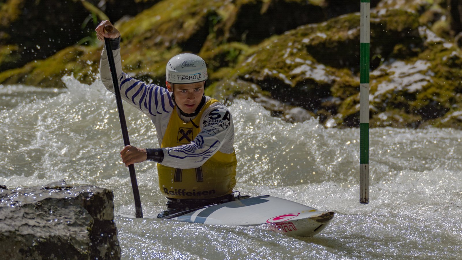 Slalom kayaker driving through a gate in fast water